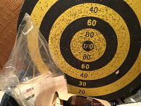 Photo of vintage dartboard with visible wear, yellow and black scoring areas with numbers up to 80.