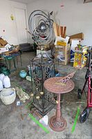 Photo showing all items in lot in a garage, including the metal globe sculpture, sundial, and chimes.