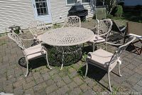 Wide shot of round cast metal table with five matching arm chairs on patio