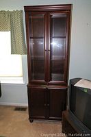 Front view of the tall glass front cabinet showing double beveled glass doors and lower solid doors.
