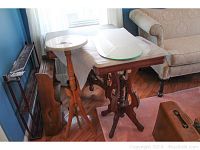 Three marble and stone top tables of various sizes with carved wooden legs shown from the side, arranged near window and sofa.