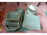 Photo showing stacked square plates and bowls with the hobnail textured edges and blue-green glaze.