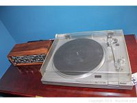 Sony PS LX 2 turntable with dust cover and wooden amplifier on wood surface.