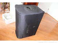 Closed black fabric roller bag case standing on hardwood floor.