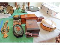 Overview of multiple wooden trinket boxes and keepsake boxes of various shapes and finishes, arranged on a green and white surface.