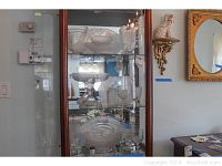 Display cabinet with various clear pressed depression glass pieces including large serving bowls, platters, and pitchers, showing overall lot contents.