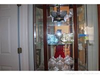 Wooden display cabinet with multiple clear lidded compotes on lower shelves and colored trays above