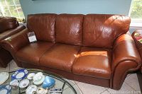 Front view of cognac brown leather sofa with three seat and back cushions