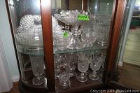 Cabinet shelf with large footed dessert dish atop shelf, goblets below