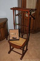 Full view of vintage wooden Spor valet stand with woven seat used for storage and hanging bars.