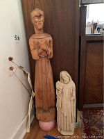 Two religious statues side by side: a taller wooden statue and a smaller Alvastone statue, showing overall size and detail.