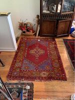 Overview of the entire Persian wool rug laid on wooden floor in room showing size and condition.