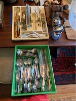 Overview of two utensil trays with flatware, ceramic spoons and wooden knife block