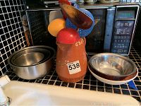 Terracotta pitcher, stainless steel mixing bowls, and serving utensils sitting on a kitchen countertop.
