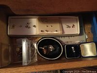 Jewelry drawer with rings, earrings, and pendants arranged in boxes and loose.