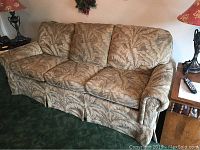 Front and side view of the sofa showing overall design, fabric, and attached back cushions.