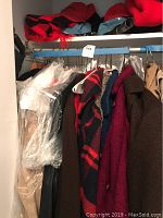 Wide view of women's coats on hangers showing various colors and styles including beige, brown, red, and plaid patterns.