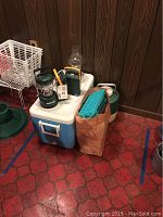 Full lot of cooler with water jug, ice trays, and lights on top and inside a paper bag