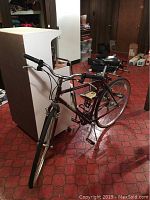 Full view of the bike showing maroon frame, handle bars, seat, and front and rear tires.