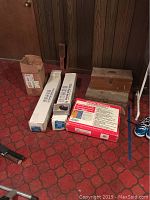 Photo of wooden tool boxes, plastic sheeting boxes, and RESQ LADDER box on red patterned floor.