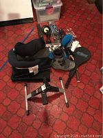 Photo of lot items arranged on floor with black tennis racket cover marked 'Prince Synergy Pro' and other various health and sports equipment visible.