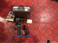 Overview photo of all items in the lot: Smith Corona electric typewriter in carrying case, Sharp calculator, desk lamp, and two electric pencil sharpeners on red patterned floor.