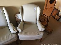 Full view of the light blue wingback chair with cushioned armrests and wooden legs, showing overall condition and style.