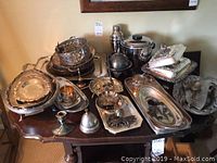 Full overview of table with stacked trays, baskets, barware and serving pieces
