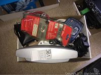 Photo of box containing Bose SoundDock Series 2 iPod speaker, various cables and black device likely modem.