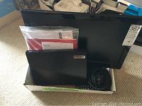 Toshiba 19 inch LCD TV with stand and remote control, cables, and user manuals inside a box.
