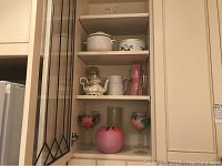 Shelf with hand painted wine glasses and pink satin glass bowl with pitchers and teapot