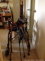Nexus fold-up walker with seat and hand brakes with walking sticks and canes leaning against it in hallway