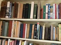Three shelves filled with assorted hardcover and paperback books covering various topics including fiction, religion, and reference.
