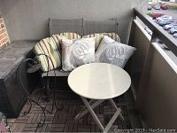 Photo showing 2-seat patio glider with striped and floral cushions, round wood folding table, and Keter deck box.