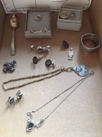 Overview photo showing entire lot with rings, earrings, cuff links, necklaces, brooch, large spoon and napkin ring.
