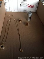 All items laid out in cardboard box including two necklaces, two rings and storage tin