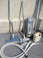 Full setup showing the vacuum cleaner main unit, hose, extension wands, floor heads, and other accessories spread out on ground