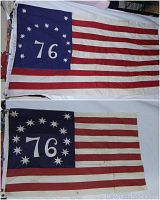 Two vintage USA 76 flags displayed, showing the blue canton with '76' surrounded by 13 stars and red and white stripes, with visible marks and dirt on the cloth.