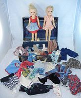 Two IDEAL Toni Walker 14 inch dolls and many pieces of assorted doll clothing laid out in front of a vintage doll carrying case.