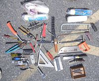 Photo showing assorted hand tools including hammers, pliers, measuring squares, screwdrivers, pipe cutter, paint rollers.