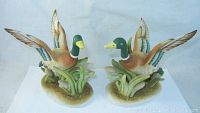 Pair of Lefton mallard duck figurines facing each other displaying both from front and side angles.