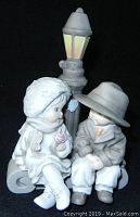 Front view of ENESCO porcelain figurine showing seated children and lamppost
