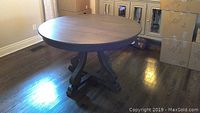 Front view of the round wooden dining table showing the full tabletop and curved leg base with cross beams.
