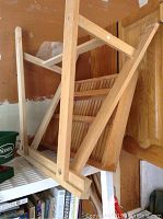 Wooden slatted shelf leaning against a wall with various other items nearby.