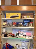 Shelf with tile cutter box, wooden miter box, insulation kit, brushes, wallpaper kit, and assorted hardware items.