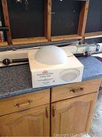 Indoor Lighting ceiling light in box and shower rod with curtain rings on countertop.