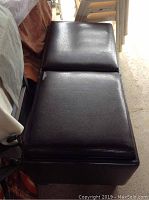 Full view of brown storage ottoman showing two flip over tray tops and rectangular shape.