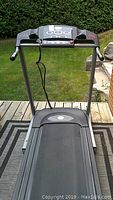 Front view of the treadmill showing the walking belt, handrails, and control console above.