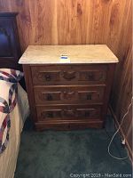 Frontal view of vintage wood dresser with marble top, showing wood carved details and drawer pulls.