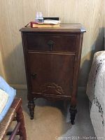 Front view of solid wood vintage rosewood nightstand with keyhole drawer and carved lower panel.
